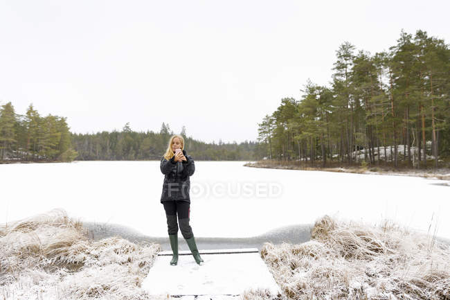 Mujer joven tomando selfie frente al lago en la nieve - foto de stock