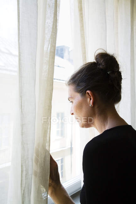 Жінка дивиться крізь вікно, вибірковий фокус — стокове фото