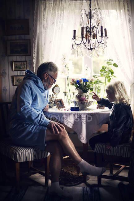 Grandfather and granddaughter at table with flowers — Stock Photo