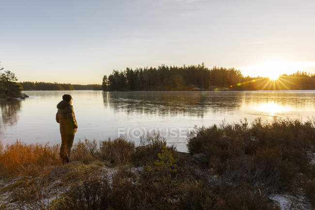 Mulher madura de pé ao lado do Lago Skiren ao pôr do sol na Suécia — Fotografia de Stock