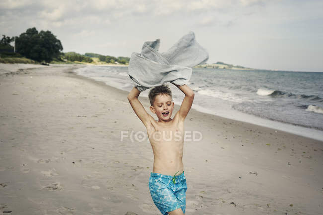 Ragazzo che porta asciugamano sulla spiaggia, messa a fuoco selettiva — Foto stock