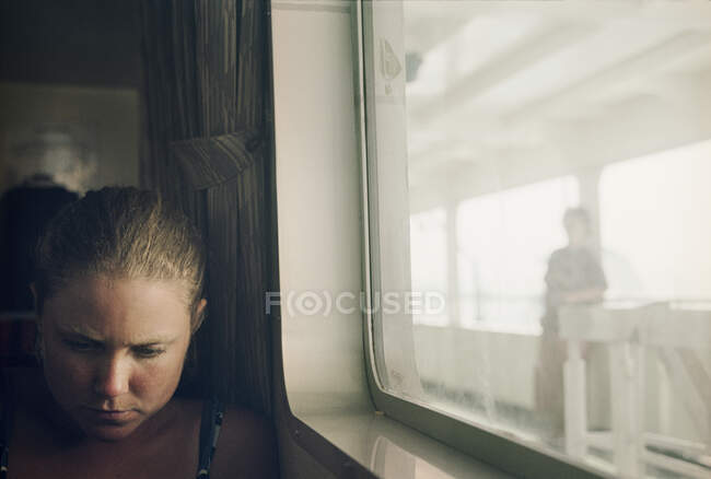 Mujer joven sentada por ventana en el tren - foto de stock
