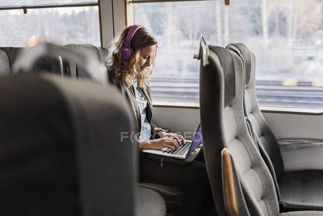 Young woman traveling on train using laptop — Stock Photo