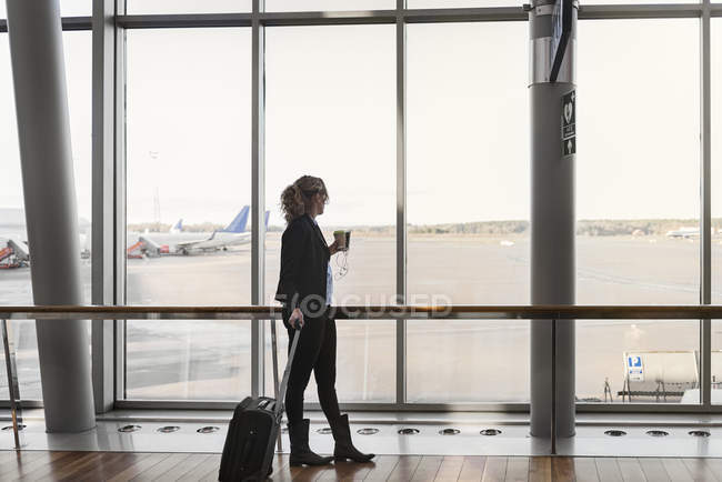Жінка з валізою і смартфоном в аеропорту — стокове фото