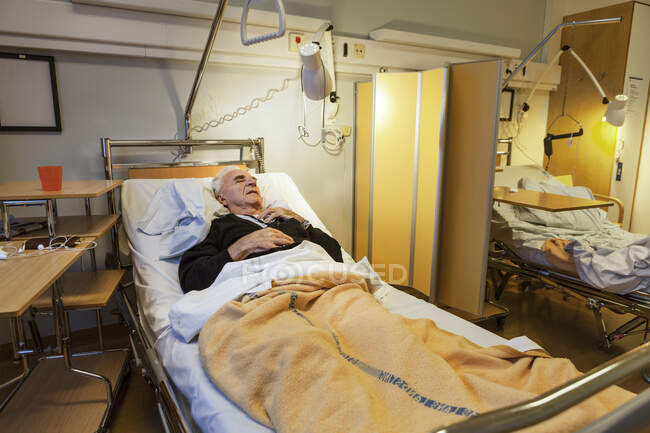 Старший лежит на больничной койке — стоковое фото