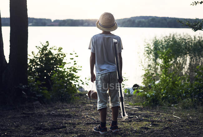 Garçon tenant canne à pêche par lac — Photo de stock