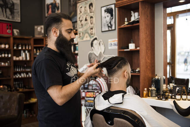 Cabelo de corte de barbeiro do cliente na barbearia — Fotografia de Stock