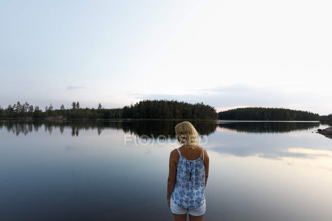 Frau steht am See in Schweden — Stockfoto