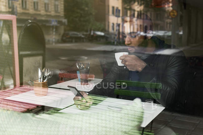 Young man with smart phone drinking coffee in cafe — Stock Photo