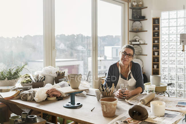 Женщина за столом в мастерской по гончарному делу, избирательный фокус — стоковое фото