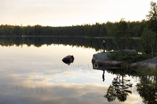 Frau steht bei Sonnenuntergang in Schweden am See — Stockfoto