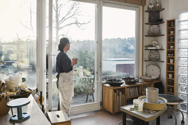Mujer por ventana en taller de cerámica, enfoque selectivo - foto de stock