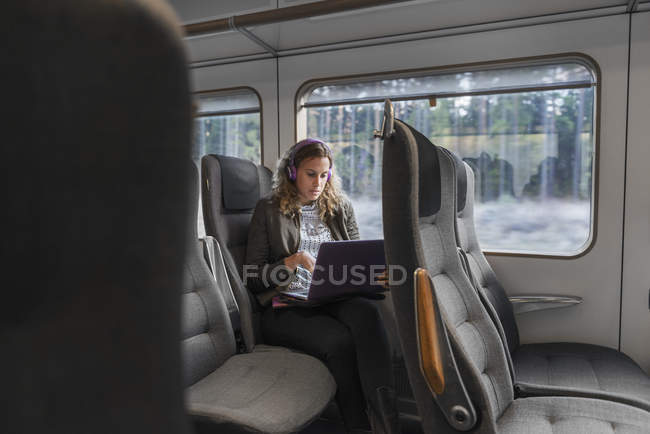 Young woman traveling on train using laptop — Stock Photo