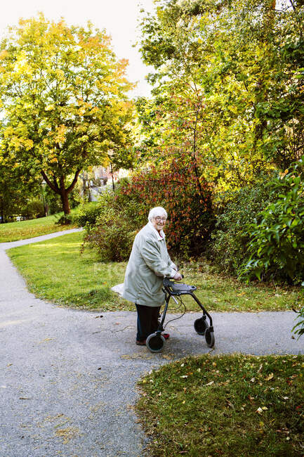 Femme âgée utilisant un cadre de marche marchant dans le parc — Photo de stock