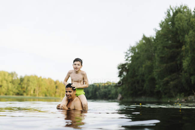 Sohn auf den Schultern des Vaters im See Kappemalagol, Schweden — Stockfoto