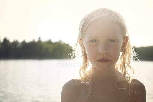 Girl back lit by sunbeam in front of lake — Stock Photo