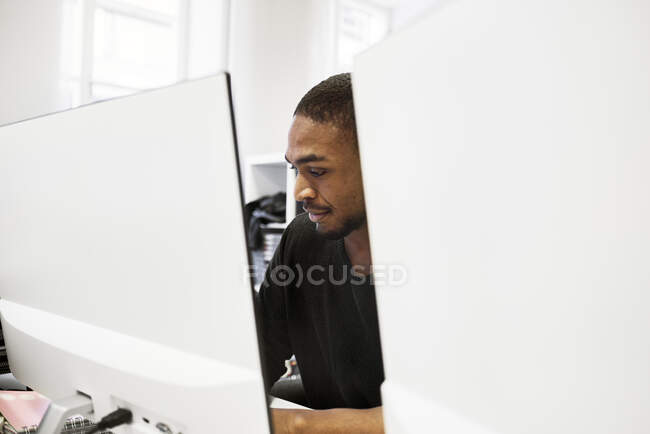 Hombre adulto medio que utiliza el ordenador en el cargo - foto de stock