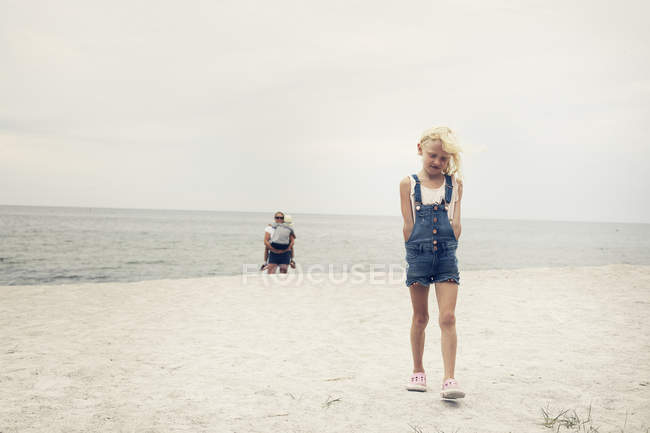 Chica caminando delante de su madre y hermana en la playa - foto de stock