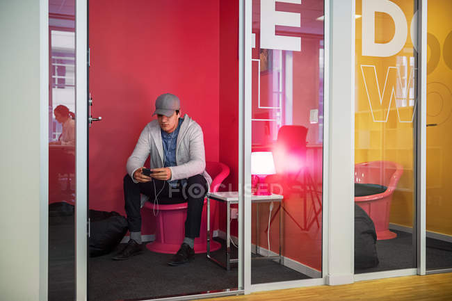 Hombre joven usando el teléfono inteligente en la oficina - foto de stock