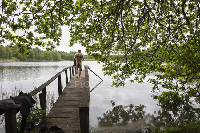 Hombre caminando en embarcadero en el lago Verkasjon, Suecia - foto de stock