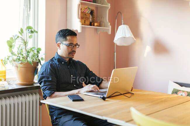 Чоловік використовує ноутбук за обіднім столом — стокове фото