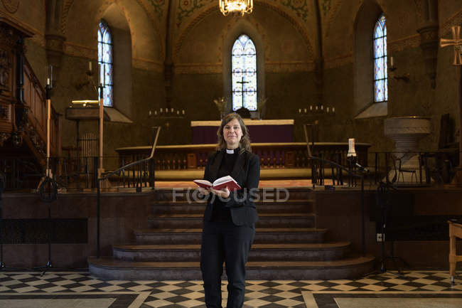 Priest with bible in church, selective focus — Stock Photo