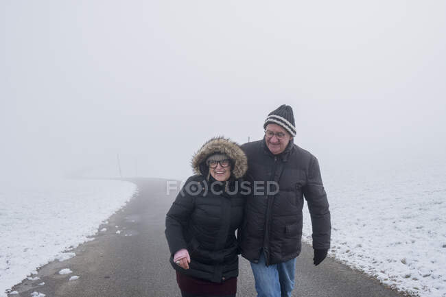 Couple de personnes âgées sur route dans la neige — Photo de stock