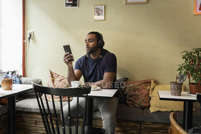 Молодой человек слушает музыку в кафе — стоковое фото