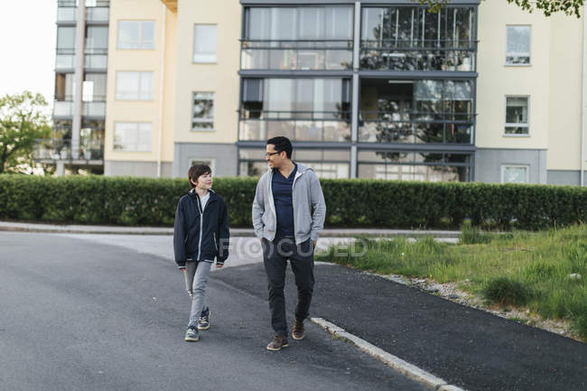 Padre e hijo caminando en una calle de la ciudad - foto de stock