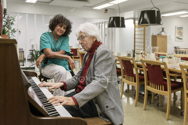 Senior woman playing piano in rest home — Stock Photo