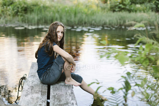 Menina sentada no molhe, foco seletivo — Fotografia de Stock