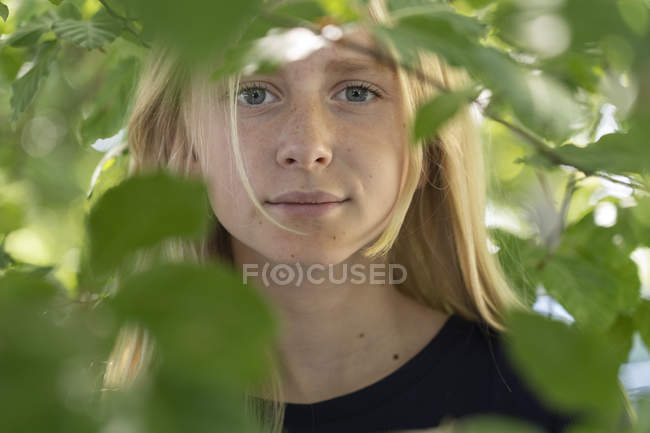 Portrait of teenage girl behind branches — Stock Photo
