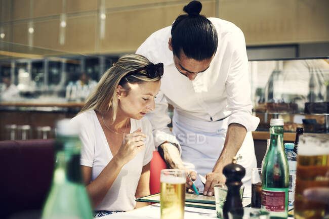 Офіціантка, яка допомагає жінці з меню в ресторані 