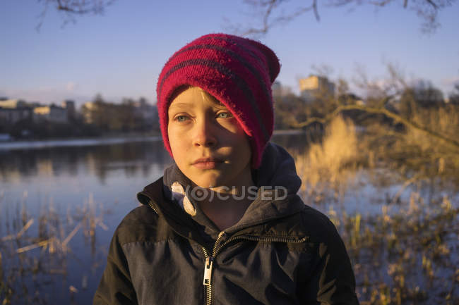 Niño por lago, enfoque selectivo - foto de stock