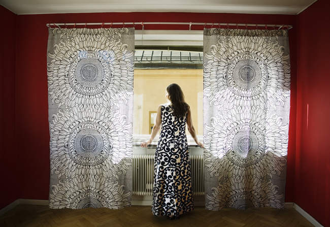Женщина смотрит через окно, вид сзади — стоковое фото