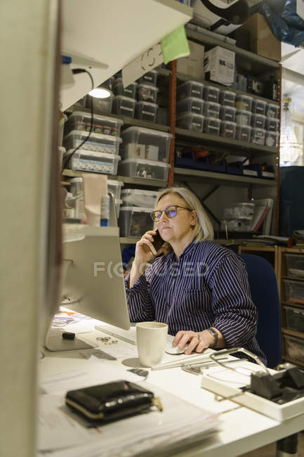 Goldsmith taking phone call and using computer — Stock Photo
