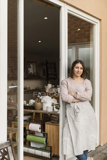 Woman leaning on door of pottery workshop — Stock Photo