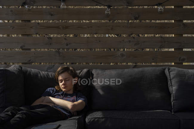 Teenage boy wearing earphones and sleeping on sofa — Stock Photo