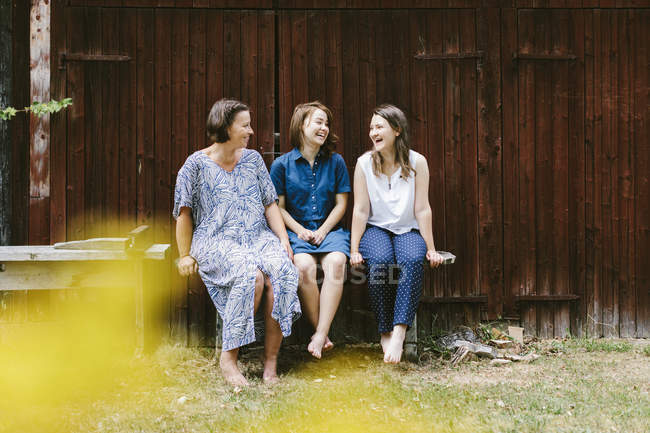 Madre e hijas sentadas en el banco - foto de stock