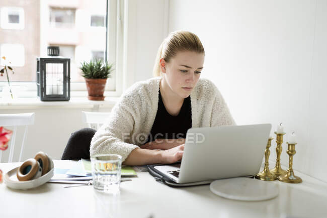 Junge Frau benutzt Laptop am Tisch — Stockfoto