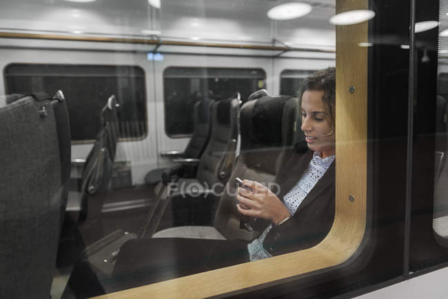 Mujer usando teléfono inteligente en tren - foto de stock