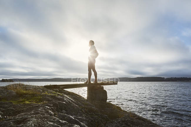 Giovane donna in piedi accanto al lago — Foto stock