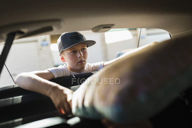Мальчик разгружает багажник автомобиля, выборочный фокус — стоковое фото