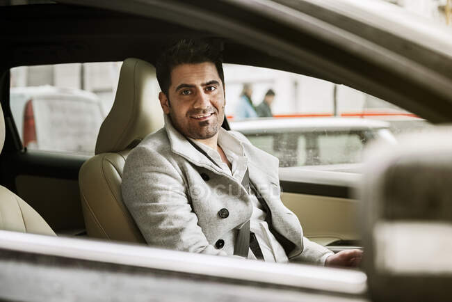 Homem sentado no carro e sorrindo para a câmera — Fotografia de Stock