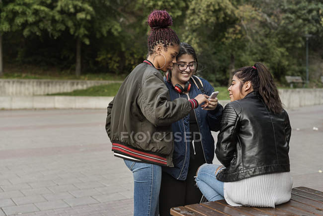 Adolescentes usando telefone inteligente no parque — Fotografia de Stock