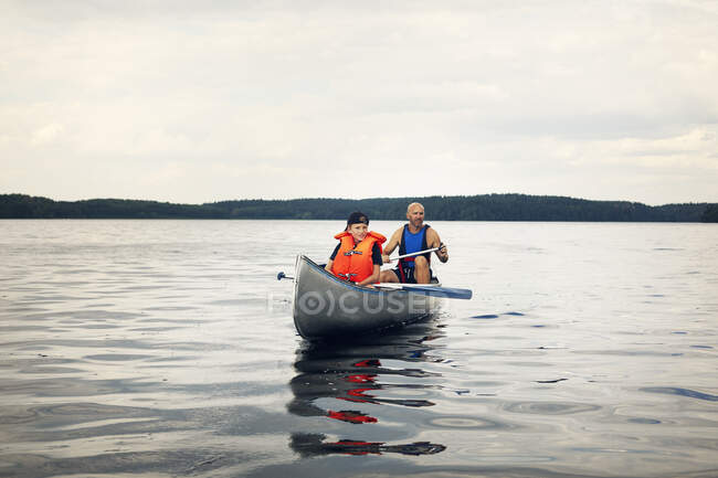 Pai e filho canoagem no lago no dia nublado — Fotografia de Stock