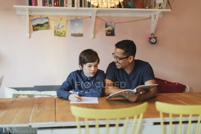 Vater hilft seinem Sohn bei den Hausaufgaben — Stockfoto