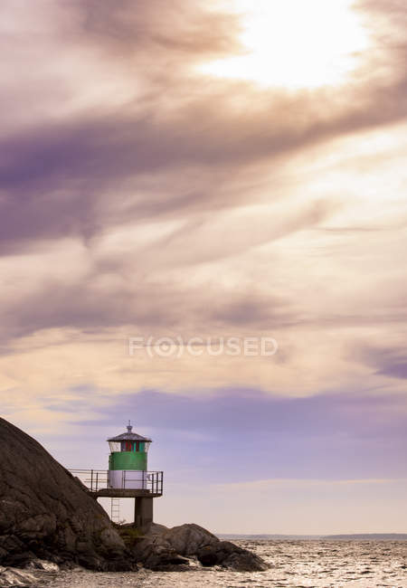 Lighthouse on rocks by sea during sunset in Kanholm Bay, Sweden — Stock Photo