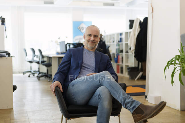 Portrait d'un homme d'affaires assis en fauteuil et souriant à la caméra — Photo de stock