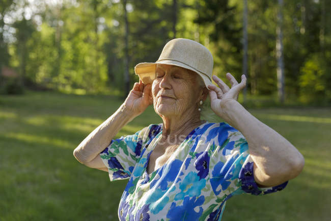 Senior woman wearing sun hat in field — Stock Photo